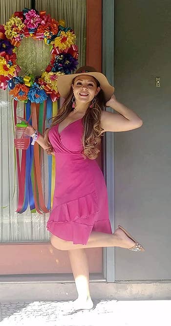Reviewer wearing hot pink spaghetti strap dress with V-neck and ruffles at the bottom outside