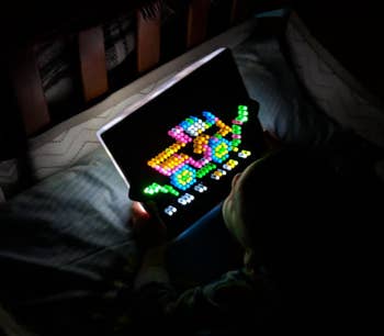 reviewer's child playing with the toy in bed