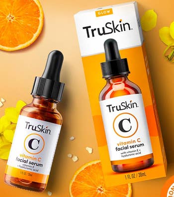 TruSkin Vitamin C serum bottle beside its packaging, with citrus slices and flowers around it