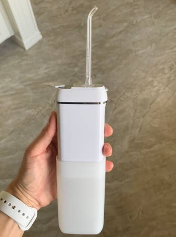 A reviewer holding the flosser with a clear nozzle