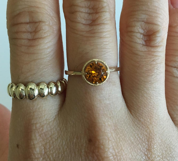 Reviewer photo of the ring with a gold band and round orange stone