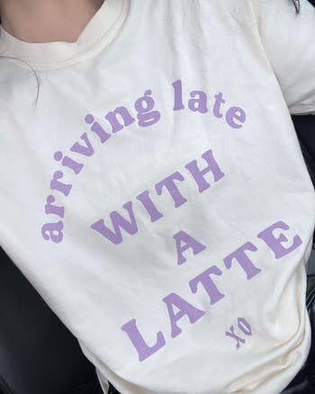 a tan graphic tee with lavender writing on it that says 