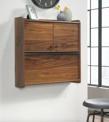Wall-mounted wooden cabinet with drop-down doors, showcasing minimalist design ideal for space-saving storage solutions