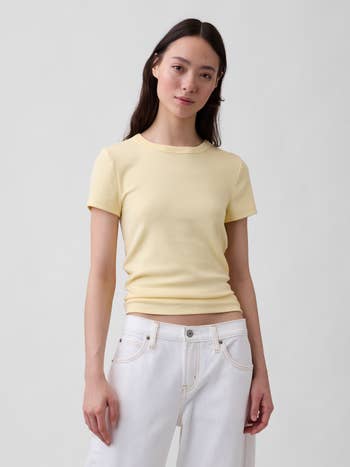 Person wearing a fitted short-sleeve garment and achromatic pants poses confidently