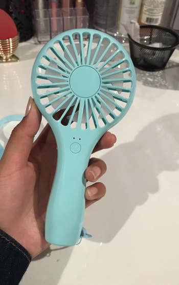a reviewer holding the blue fan in their hand