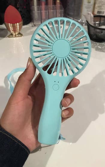 a reviewer holding the blue fan in their hand