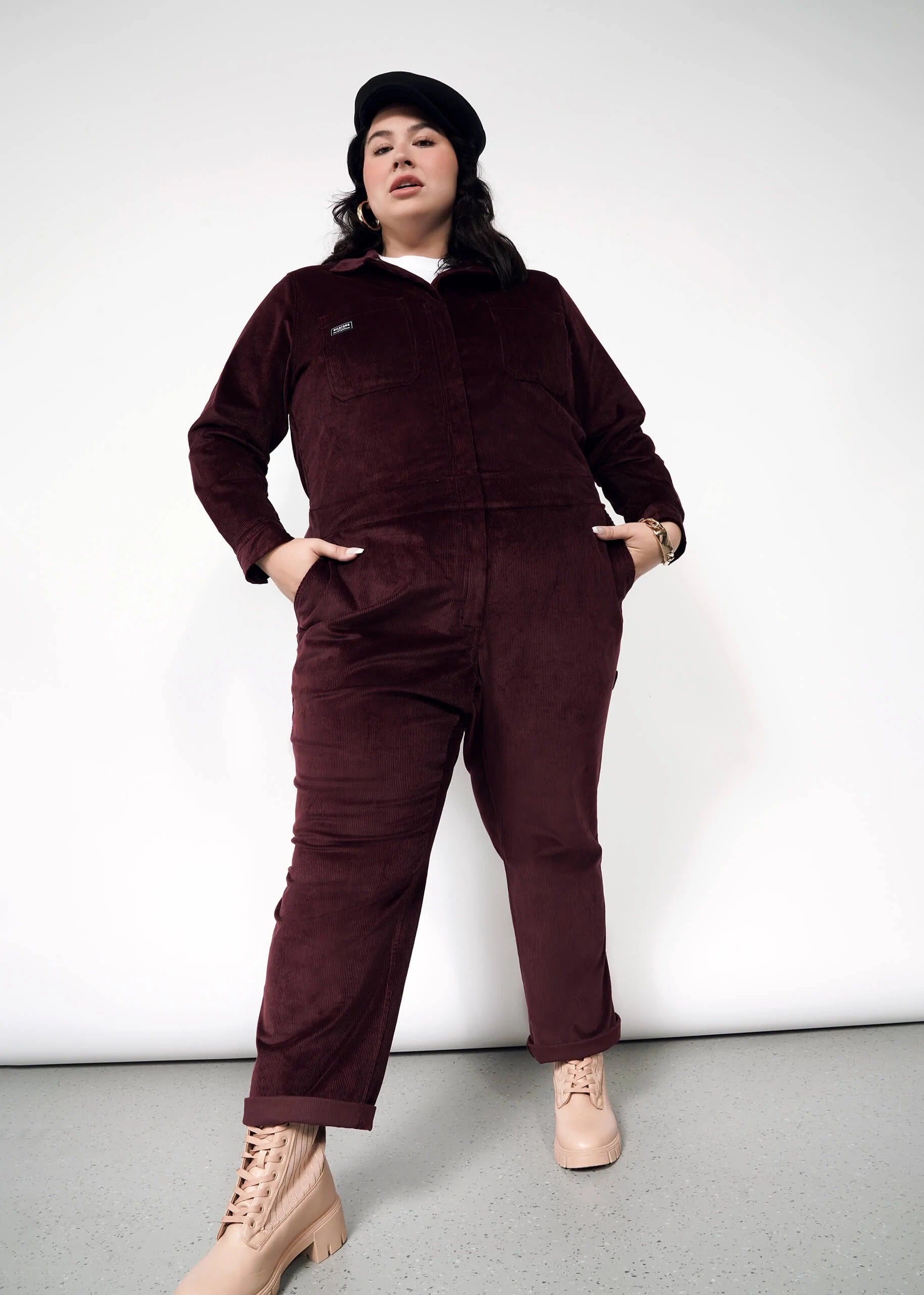 a plus size model wearing the merlot colored corduroy coveralls