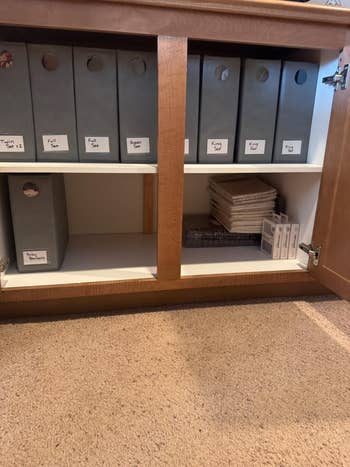 Organized retention  with labeled binders and assorted  stacked items successful  a wood   cabinet, suitable for location  oregon  bureau   use