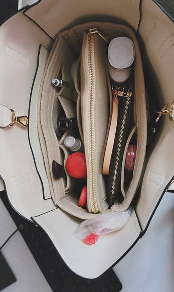 a reviewer photo of the open tote with the purse organizer inside and filled with cosmetics, a wallet, and more 