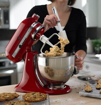 model using spatula on dough in the red KitchenAid mizer