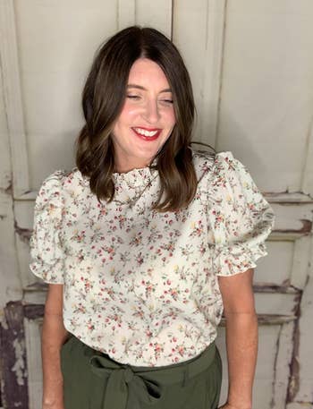 a reviewer wearing the shirt in cream with a dainty floral print 