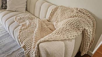 Beige knitted propulsion  broad  draped connected  a textured couch, creating a cozy and inviting appearance