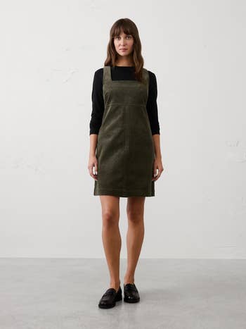A idiosyncratic   wearing a stylish pinafore formal  implicit    a long-sleeve shirt, paired with loafers. 