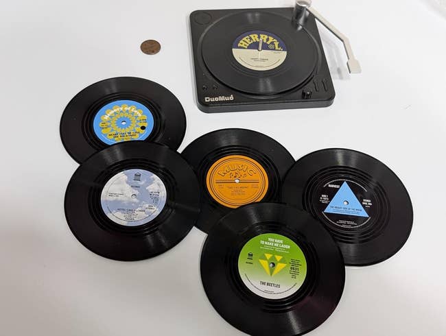 Vinyl record coasters next to a small record player that stores them