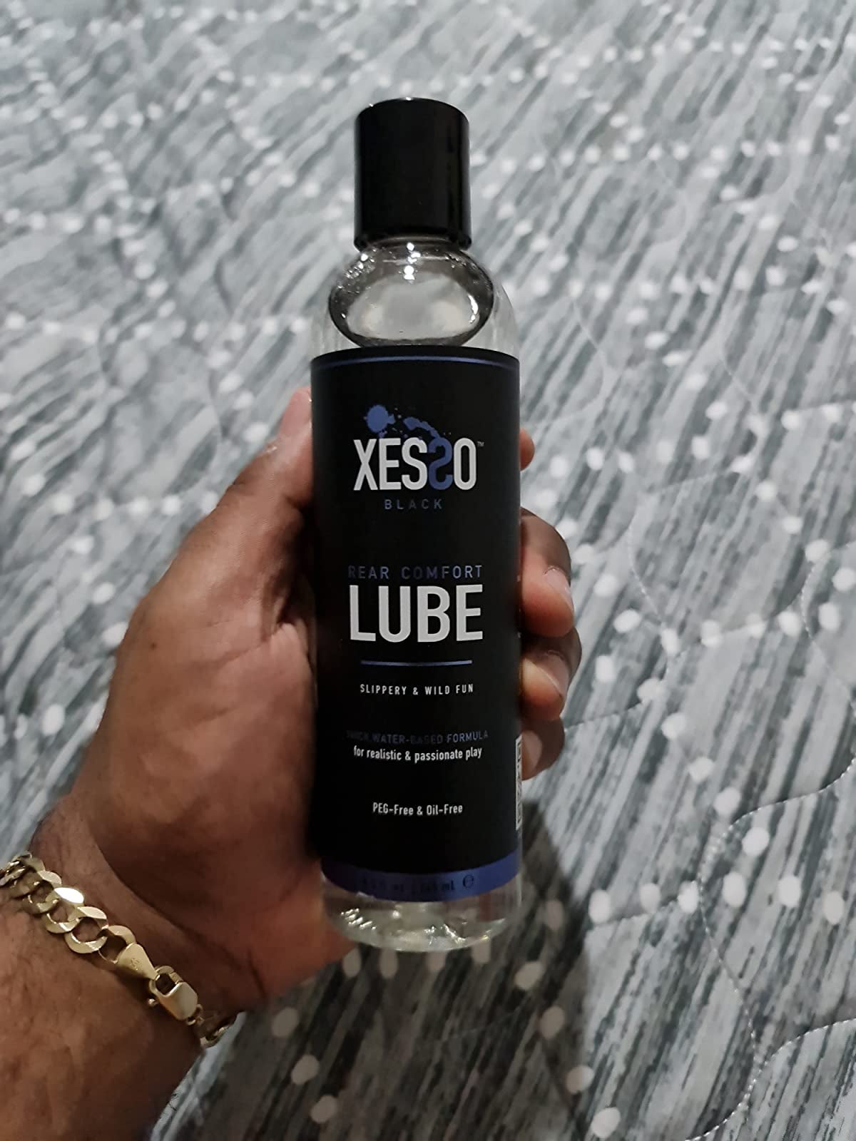 Model holding black Xesso lubricant bottle