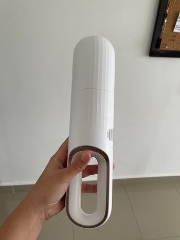reviewer holding the small white portable vacuum