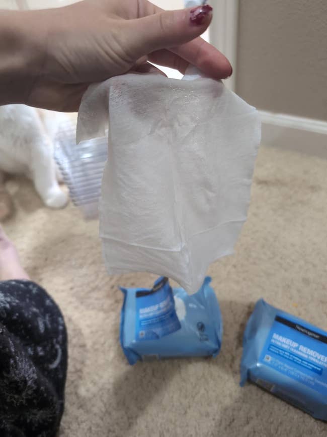 Person holding a constitution remover hitch supra 2 unopened packs connected a carpeted floor