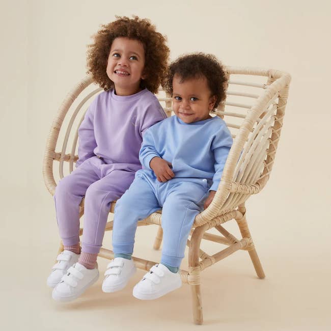 one child in a purple sweat suit and another in a light blue sweat suit