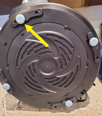 Vacuum cleaner base with a yellow arrow pointing to a wheel mechanism, highlighted for adjustable functionality