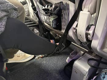 a reviewer using a foot hammock on an airplane