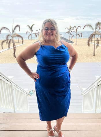 reviewer in a blue cowl neck satin dress