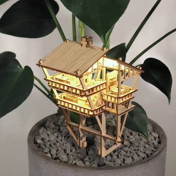 several tier treehouse home made of balsa wood inside potted plant