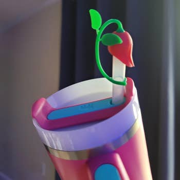 Whimsical drink tumbler with straw featuring a decorative rose top