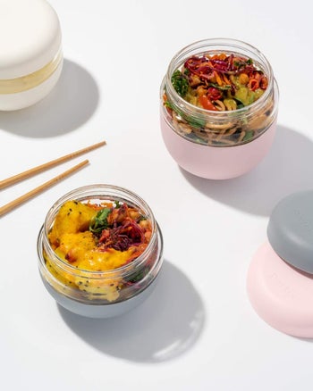 two of the containers filled with food next to a pair of chopsticks