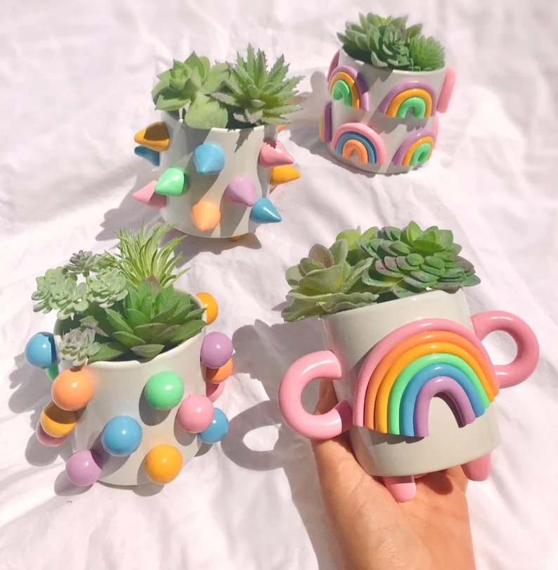 four white planters with different rainbow designs made of clay