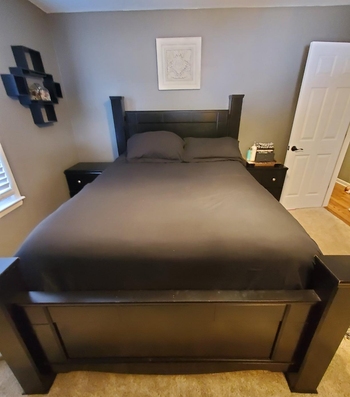 Reviewer image of product in black duvet cover and matching pillowcases and dark wood bed frame