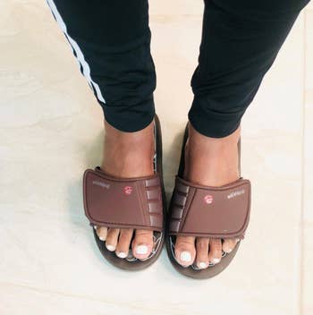 Person wearing branded slide sandals, captured from above