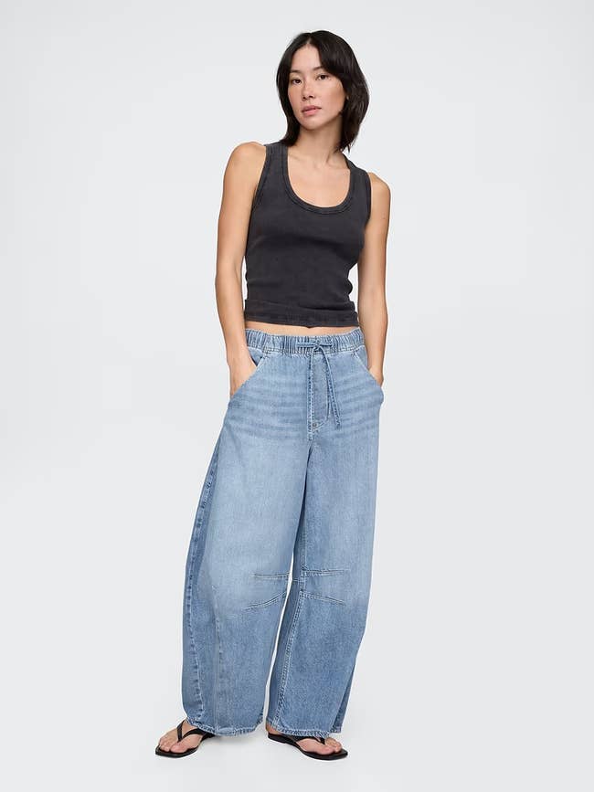 Person successful  a casual outfit wearing a vessel  apical  and wide-leg jeans, lasting  with hands successful  pockets, suitable for relaxed buying  attire