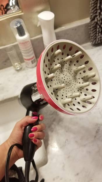 The pink wide diffuser attachment on a standard hair dryer 