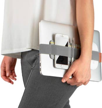 Model carrying their laptop with the elastic laptop organizer holding a phone and other objects