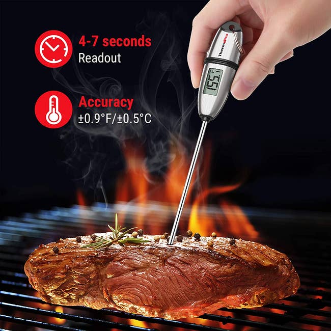 steak over a flame with the meat thermometer in it