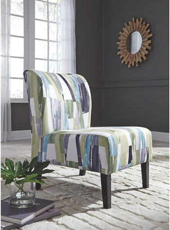 an abstract printed armless chair with green, white, and blue stripesq“class=