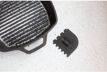 the black scraper with indents next to a grill pan