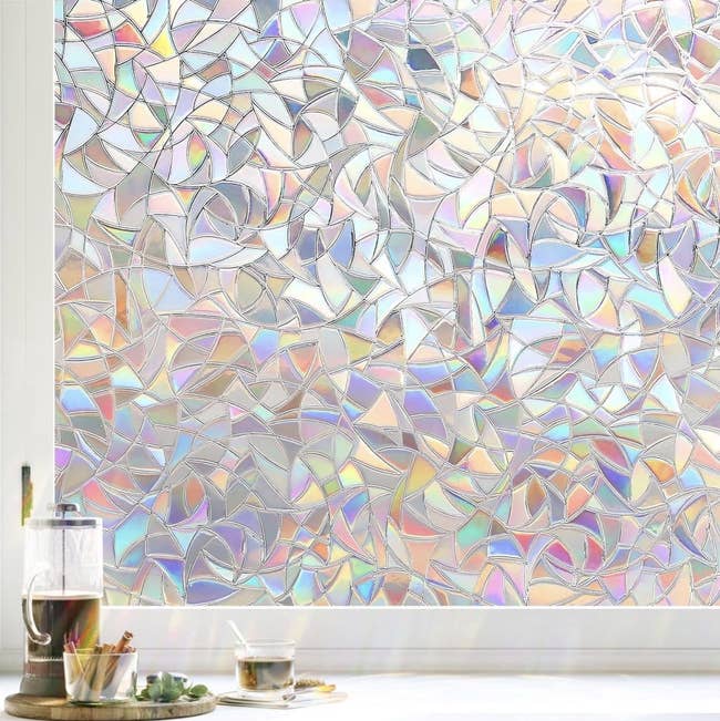 Window with abstract, frosted mosaic design, connected a countertop with a solid teapot and cup; decorative privateness movie for location decor