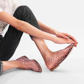 Person wearing stylish woven flats successful a relaxed airs with jeans and a casual top, highlighting the footwear's plan for a buying feature