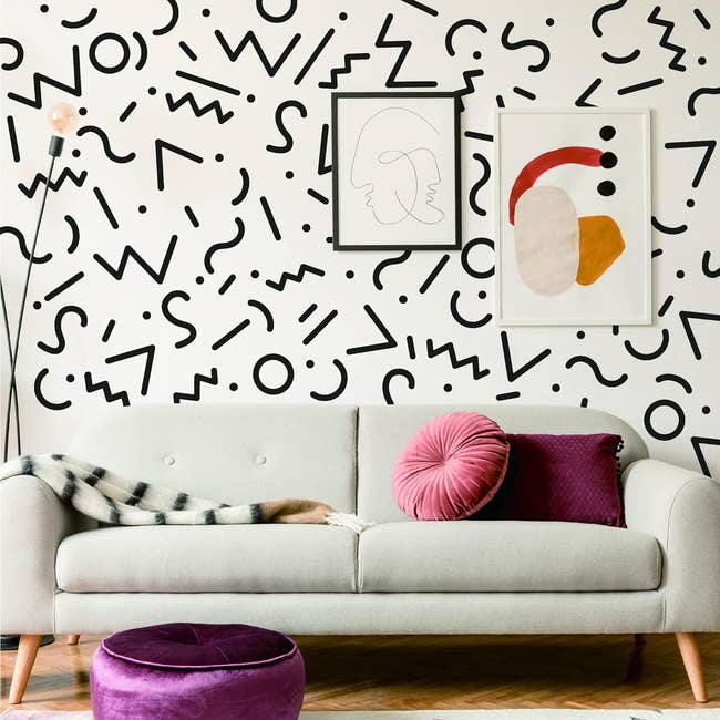 Scandinavian style living room with a neutral couch, abstract wall art, and a vibrant round cushion