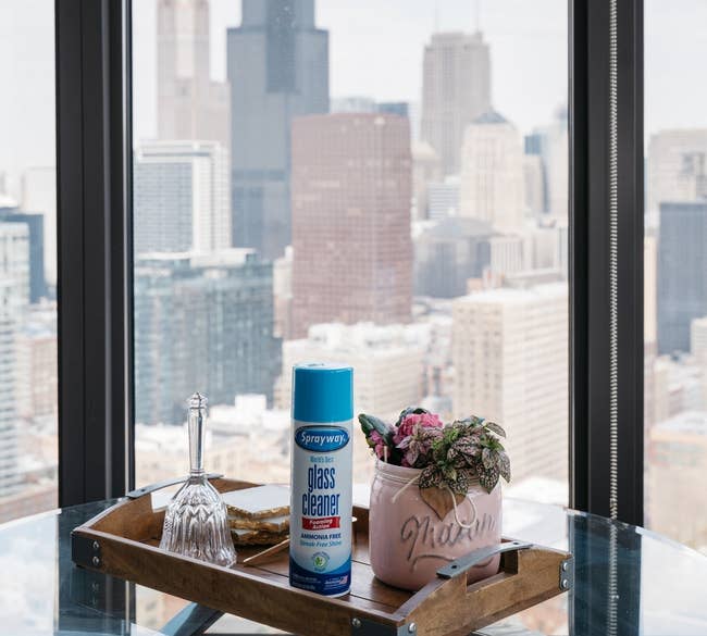 The can of cleaner on a glass table by a large window