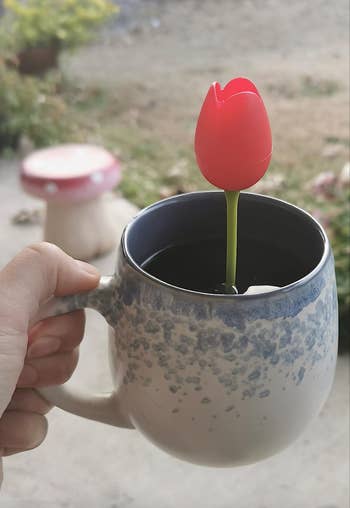 A red silicone tulip steeper popping out of a tea cup 