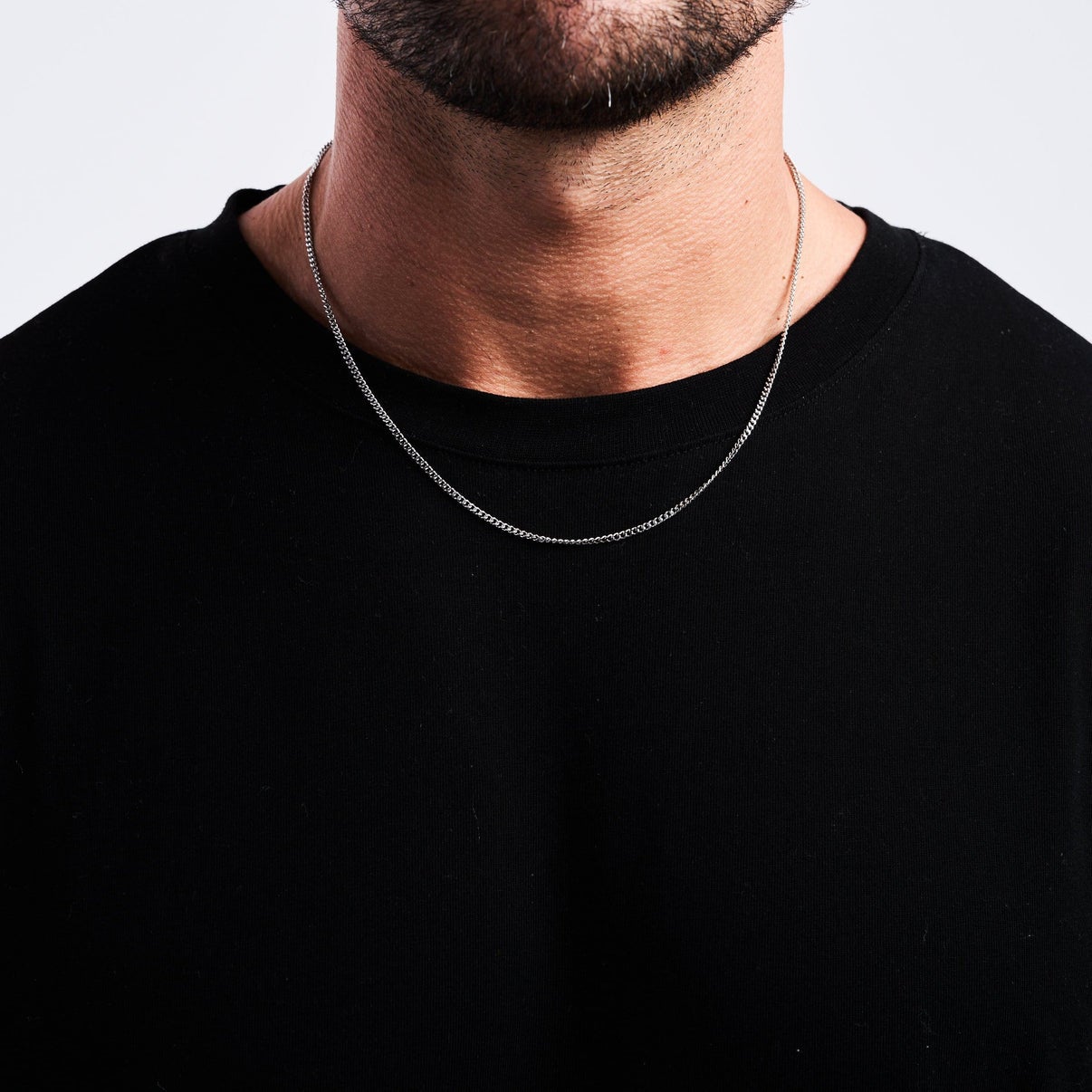 a model wearing a silver chain necklace and a black shirt
