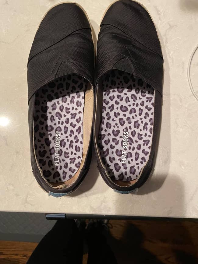 A pair of well-worn slip-on shoes with leopard print insoles