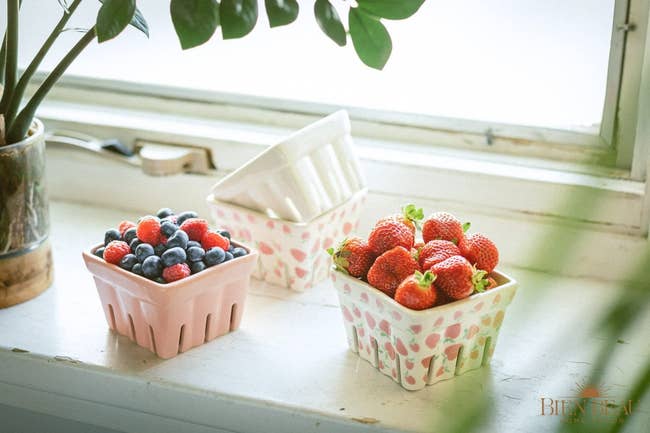 the four square ceramic baskets on a windowsill, two of which are housing fruits