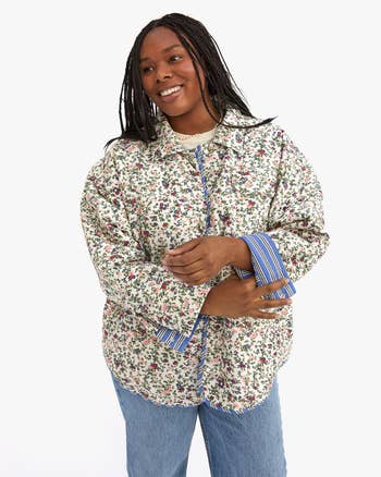 model wearing jacket reversed with majority of jacket white and multicolor floral print with striped trim showing