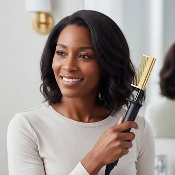 A idiosyncratic smiles portion holding a heated styling comb adjacent their hair
