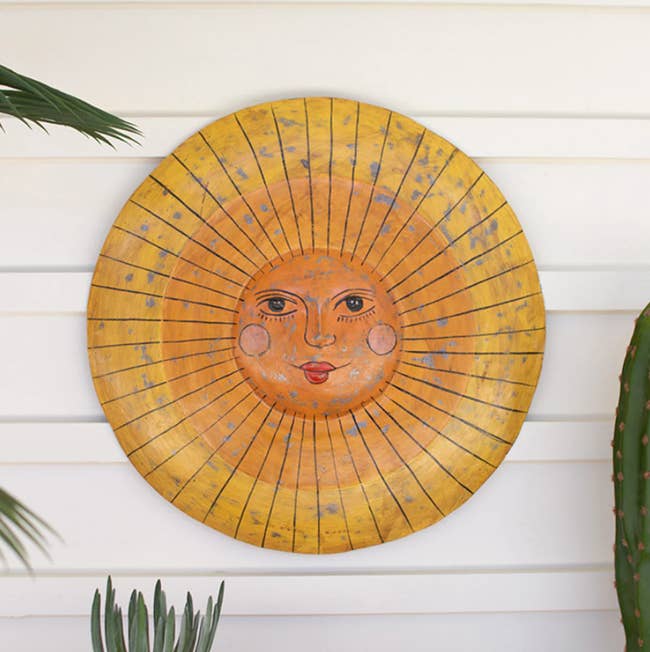 round metal wall hanging of sun with painted smiling face