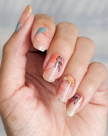 A hand displaying pastel floral nail wraps