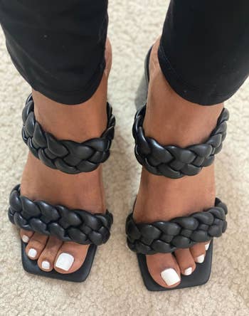 A pair of feet wearing black braided strap sandals